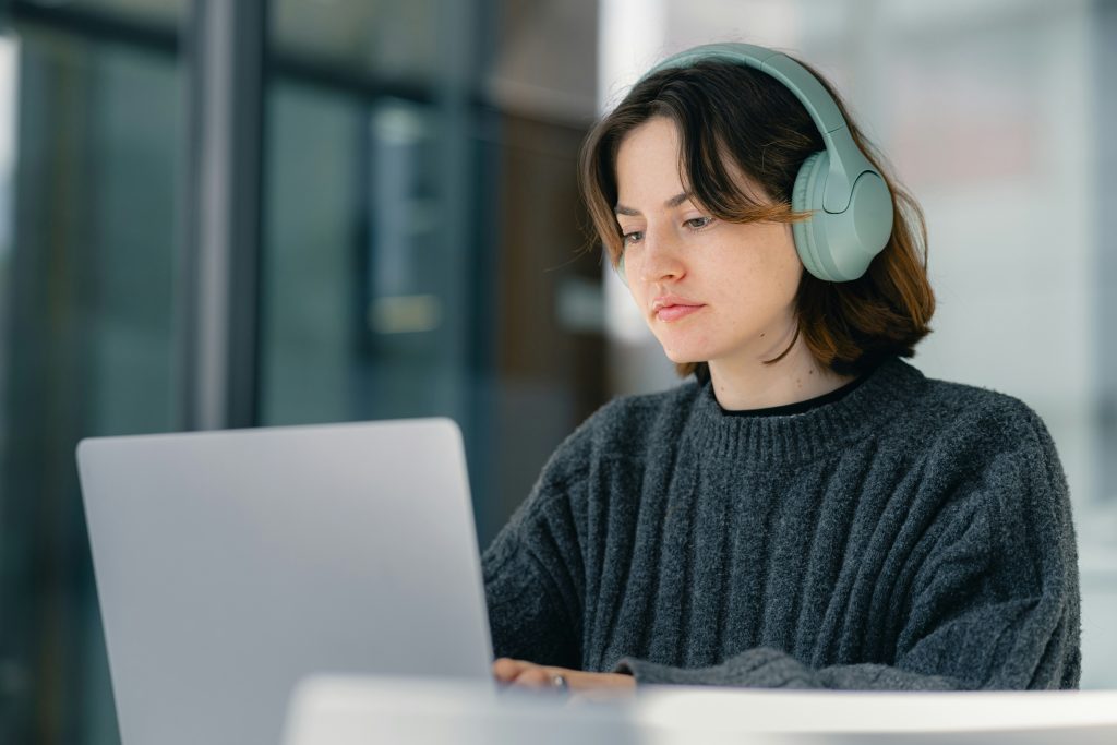 Junge Frau mit Kopfhörern am Laptop